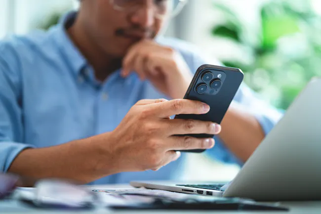 Man looking at his phone, comparing insurance prices